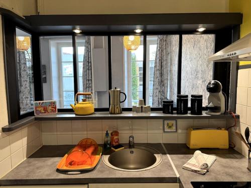 - un comptoir de cuisine avec évier et 2 fenêtres dans l'établissement ღ Cordelier - Proche du port et du marché, Spacieux & Wi-Fi, à La Rochelle