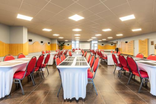a conference room with white tables and red chairs at ibis budget Paris Porte d'Aubervilliers in Aubervilliers