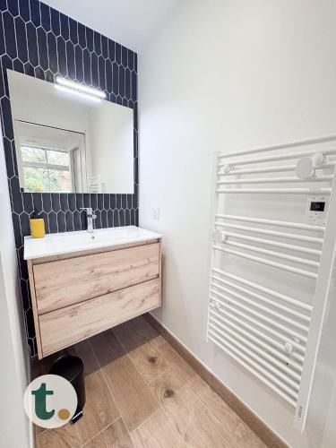 une salle de bain avec un lavabo et un miroir dans l'établissement Tranquiloue - Le Nid de Mila - 10 min du PuyduFou, aux Herbiers