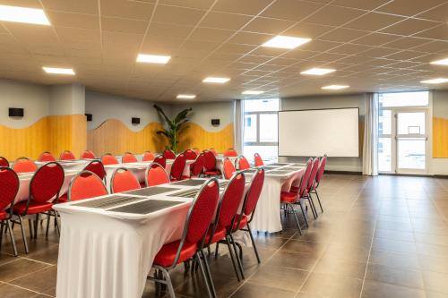 a conference room with long tables and red chairs at ibis budget Paris Porte d'Aubervilliers in Aubervilliers