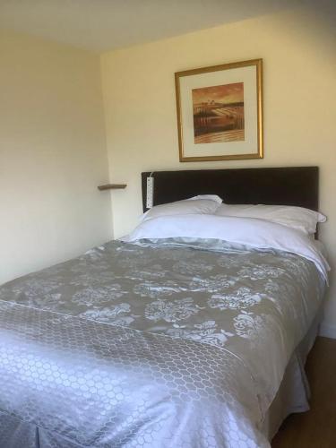 a bedroom with a white bed with a picture on the wall at Croft cabin in Fort William