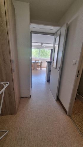 un couloir vide avec une porte ouverte sur une chambre dans l'établissement Le Petit QG, à Gruissan