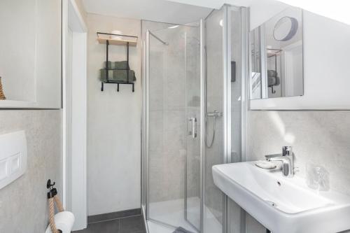 a white bathroom with a shower and a sink at Zeihäänger Stubb in Schwalmstadt