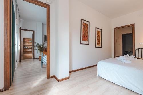 ein weißes Zimmer mit einem Bett und einem Spiegel in der Unterkunft Da Tiffany - soggiorna in centro a Gorizia con garage box e ascensore in Gorizia