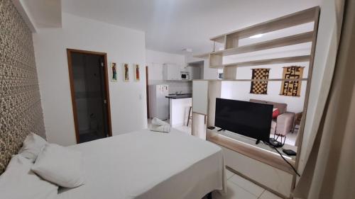 a small white room with a bed and a television at Santorini na rua do hospital Premium Mater Dei Piscina Academia Jacuzzi Parque Areiao e Goiania Shopping tudo perto in Goiânia