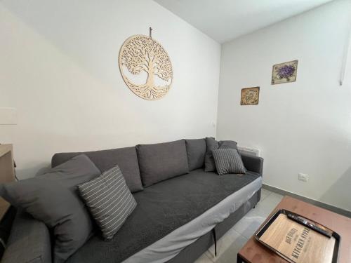 a living room with a gray couch and a tree picture on the wall at Fenix Appartement T2 40 M2 cosy RDC plein centre ville in Pierrelatte