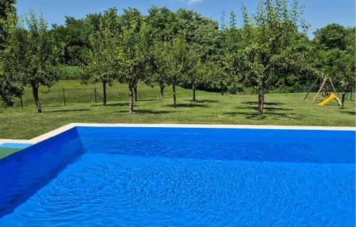 a blue swimming pool next to a park with a playground at Stunning Home In Senkovec With Sauna in Slakovec