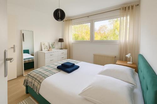 une chambre avec un grand lit blanc et une fenêtre dans l'établissement Bel appartement avec terrasse et jardin, à Vaux-le-Pénil
