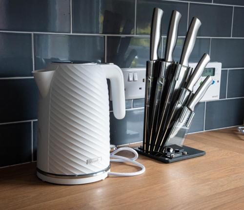 a white toaster sitting on top of a counter with knives at Stirling Street Stays in Tillicoultry