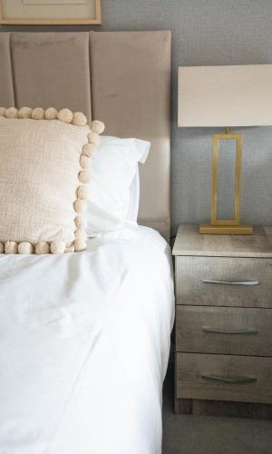 a bedroom with a white bed and a nightstand with a lamp at Stirling Street Stays in Tillicoultry