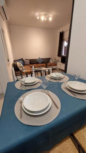 a table with plates and glasses on a blue table cloth at Il Rumore del Mare Beach House in Trinità dʼAgultu