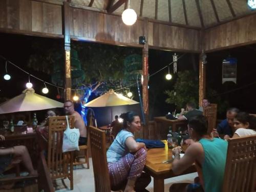a group of people sitting at a table in a restaurant at Sakti OceanView Nusa Penida in Nusa Penida