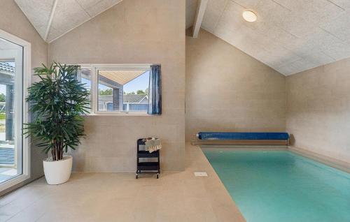 a swimming pool in a room with a plant at Pet Friendly Home In Nørre Nebel in Nørre Nebel