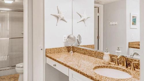 a bathroom with a sink and a mirror and a toilet at Spacious 2BR condo on Siesta Key with private beach access in Siesta Key