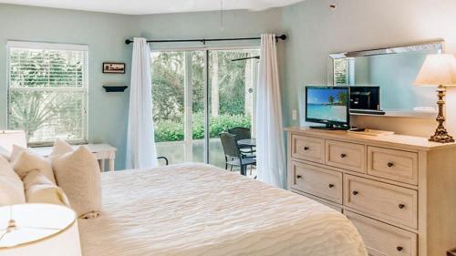a bedroom with a bed and a television and a window at Spacious 2BR condo on Siesta Key with private beach access in Siesta Key
