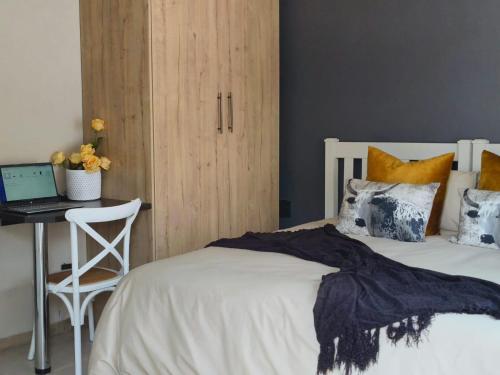 a bedroom with a bed and a desk with a laptop at Tshepang Apartments Secunda in Secunda