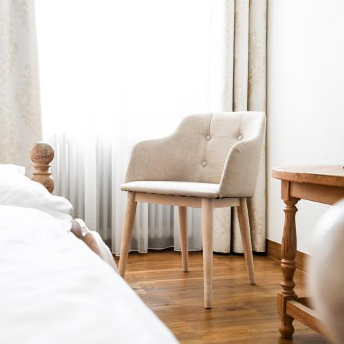 a chair sitting in a bedroom next to a window at Landhotel Adler in Deggenhausertal