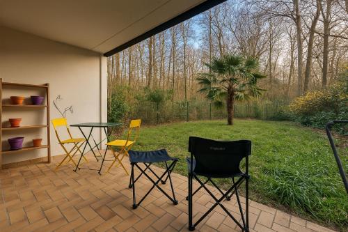 une terrasse avec des chaises, une table et un palmier dans l'établissement Bel appartement avec terrasse et jardin, à Vaux-le-Pénil