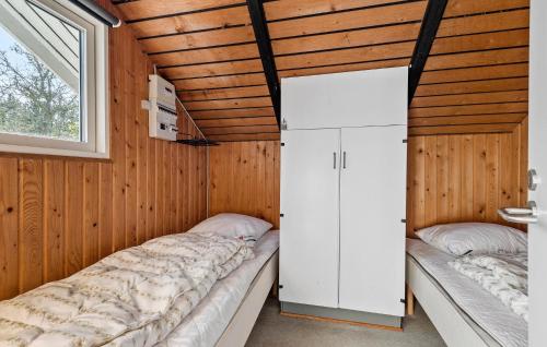two beds in a room with wooden walls and a window at Holiday Home Fanø 57 in Sønderho