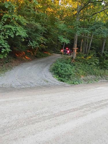 a truck driving down a dirt road with trees at Pine Hill FLX Retreat in Cohocton
