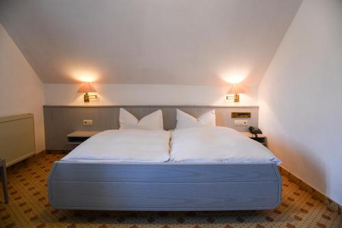 a bed with white sheets and pillows in a room at Landhotel Adler in Deggenhausertal