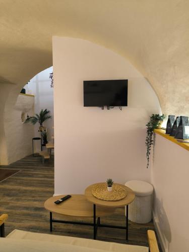 a living room with a table and a tv on a wall at Ma douce Fenière in Saint-Rémy-de-Chargnat
