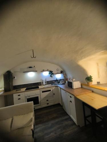 a kitchen with white cabinets and a table in a room at Ma douce Fenière in Saint-Rémy-de-Chargnat