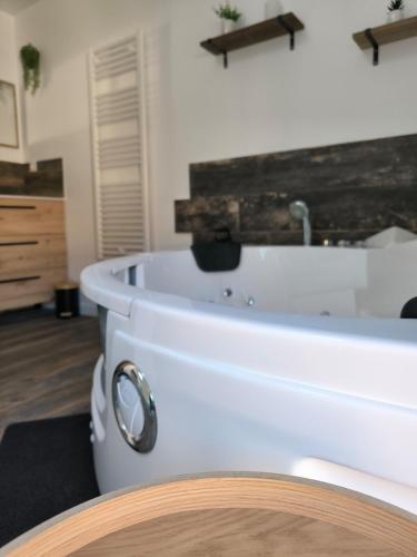 a white bath tub in a room with a table at Ma douce Fenière in Saint-Rémy-de-Chargnat