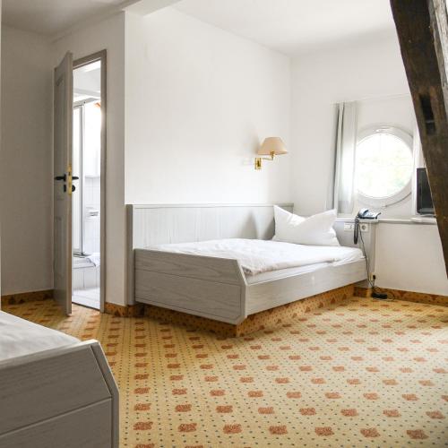 a white bedroom with a bed and a window at Landhotel Adler in Deggenhausertal