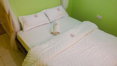 a small bed with white sheets and pillows at Olali Suites Migori in Migori