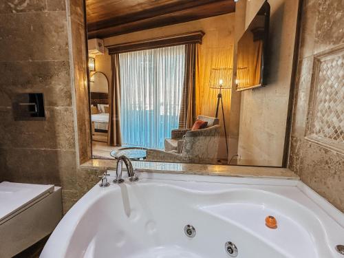a bath tub in a room with a mirror at Osmanli Cappadocia Hotel in Goreme