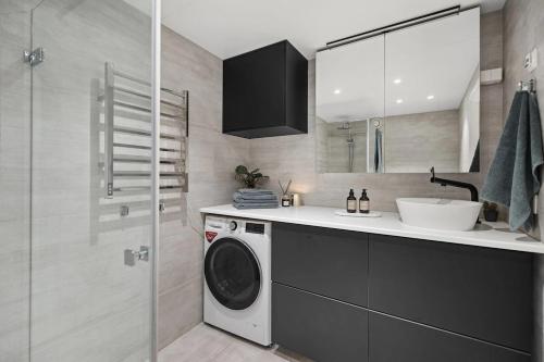 Un baño con lavadora y lavabo. en Modern 3 bedroom apartment - 4 minute walk from metro - top floor baclony view, en Oslo