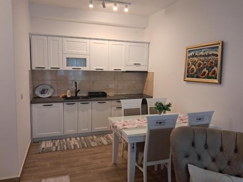 a kitchen with white cabinets and a table with chairs at Ruža Vetrova 4 in Nova Varoš