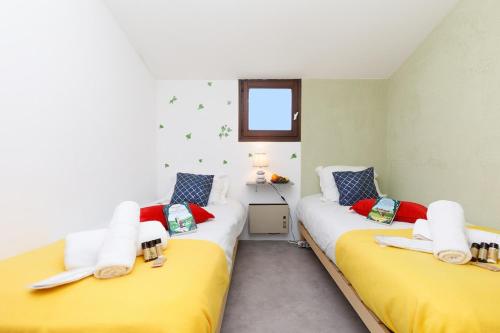 - 2 lits dans une chambre de couleur jaune et rouge dans l'établissement Saint Charles YourHostHelper, à Saint-Raphaël