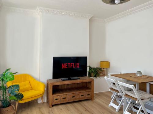 a living room with a tv and a yellow chair at Deducted 3B Flat, Fast Wi-Fi, 5 min Canning Town, near ExCel & O2 in London