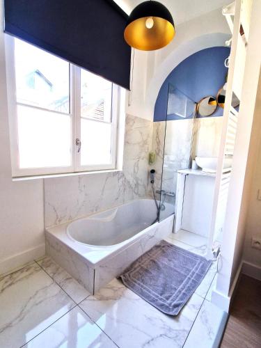 La salle de bains est pourvue d'une baignoire blanche et d'une fenêtre. dans l'établissement Les Bons Enfants 7, à Rouen