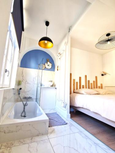 La salle de bains est pourvue d'une baignoire à côté d'un lit. dans l'établissement Les Bons Enfants 7, à Rouen