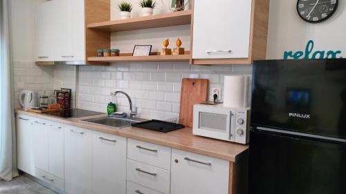 a kitchen with white cabinets and a black refrigerator at N&K Yellow Pearl Flat in Volos
