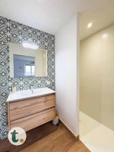 une salle de bain avec un lavabo et un miroir dans l'établissement Tranquiloue - Le Nid de Jeanelle - 10 min du PuyduFou, aux Herbiers