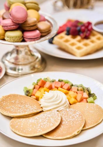 a table with plates of food with pancakes and fruit at Mandarin Oriental Ritz, Madrid in Madrid