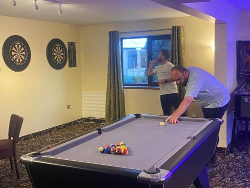 two men standing around a pool table in a room at The Gulliver's Hotel in Warrington