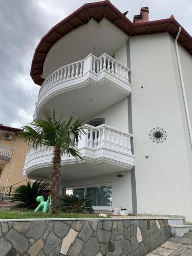 a white building with a balcony and a palm tree at SeaView Ground in Eleftheres