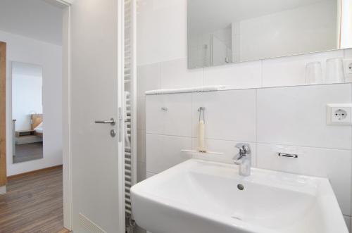 a white bathroom with a sink and a mirror at Gästehaus D i c k r e i t e r in Immenstaad am Bodensee