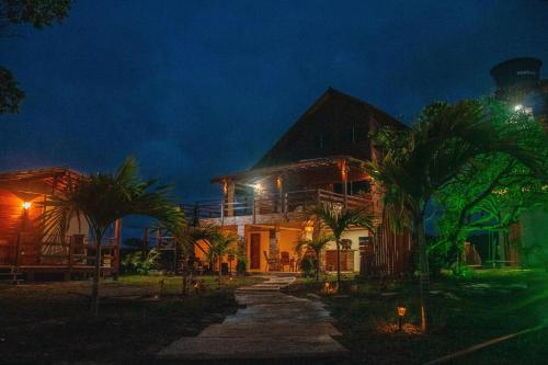 a house with palm trees in front of it at night at Chalé Casal - Pousada Rancho Matos in Santo Amaro