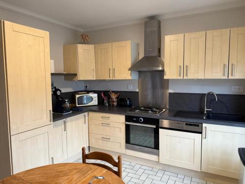 une cuisine avec des armoires en bois et une table à l'intérieur dans l'établissement Le castor - Quartier résidentiel, à Saint-Brieuc