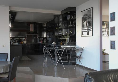 une cuisine avec des armoires noires, une table et des chaises dans l'établissement Blanche Bagnolet - CI - Calm house for 6 people, à Bagnolet