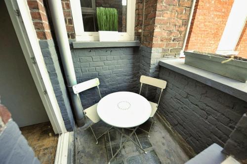 una mesa blanca y 2 sillas sentadas en un patio en T2, Centre ville, Gare 600m, Prox Lille, Terrasse, en Tourcoing