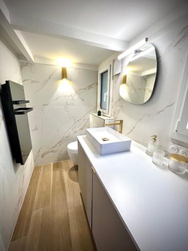une salle de bain blanche avec un lavabo et un miroir dans l'établissement YŪGEN PALLADIO - Fully renovated Studio on a prime location, Direct Beach Access, Heated Pool, Private terrace & patio, Private Parking lot, à Saint-Raphaël