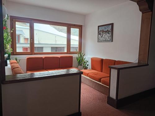 a living room with an orange couch and a window at Fiocco di sole Apartment in Sestriere
