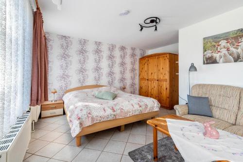 a small bedroom with a bed and a couch at Hus Tingeltut Gerd Clausen in Pellworm